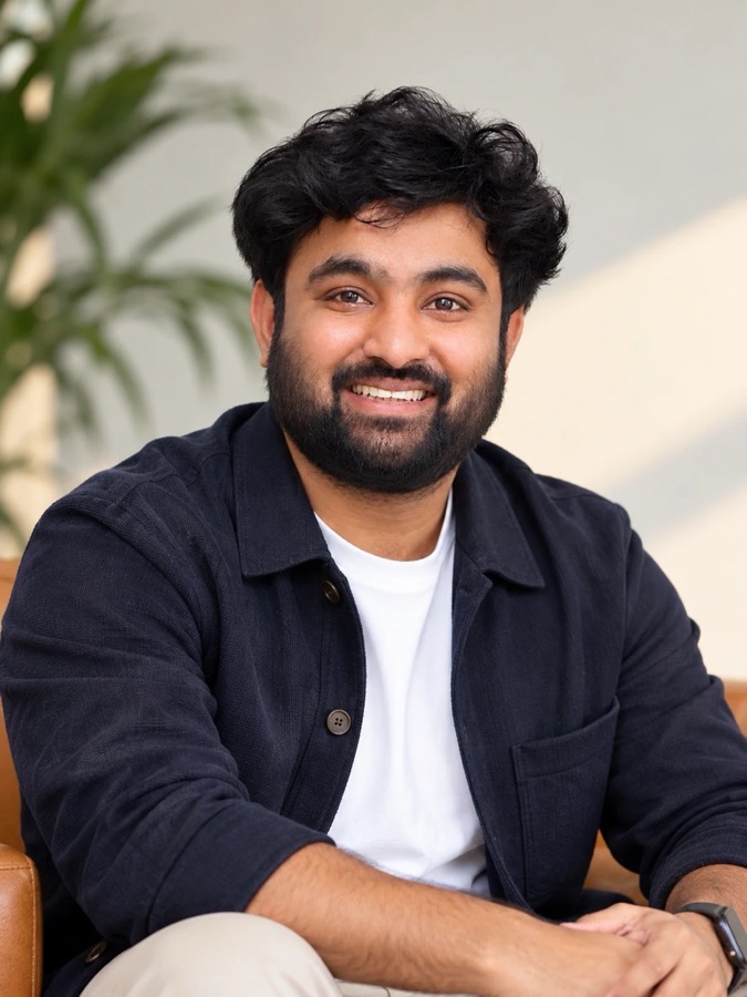 Vijay Chaganti smiling, wearing a navy jacket over a white tee